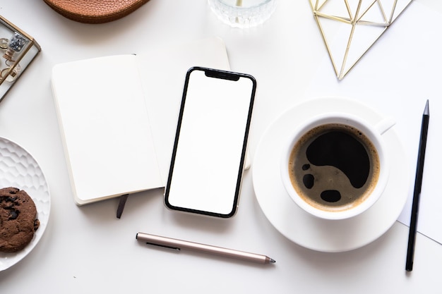 Wit kantoor aan huis tafelblad met smartphone mockup koffiekopje en notitieblok