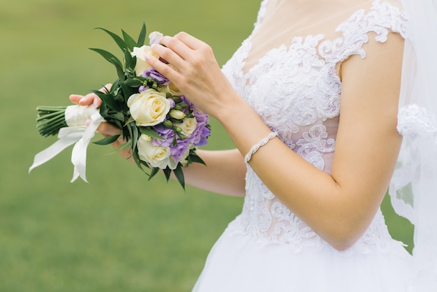 Wit lila huwelijksboeket mooi in de handen van de bruid