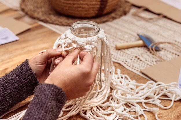 Wit macrame Jong meisje repareert de macraméknopen zodat ze niet ontrafelen