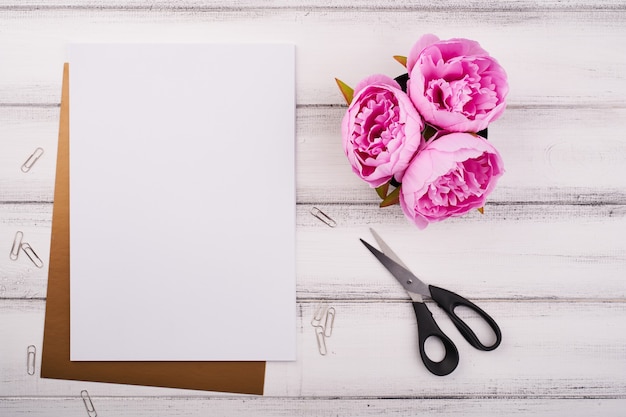 Wit papier op het houten bureau met bloem en schaar