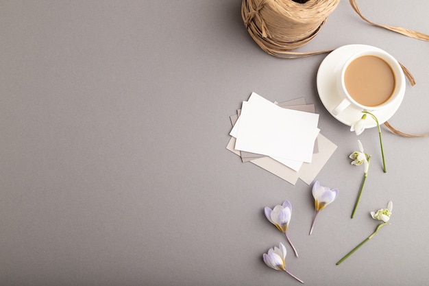 Wit papieren visitekaartje met lentekrokus en galanthusbloemen en kopje koffie