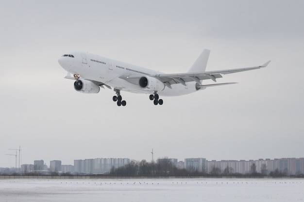 Wit passagiersvliegtuig die op luchthaven in de winter laag over de landingsbaan landen