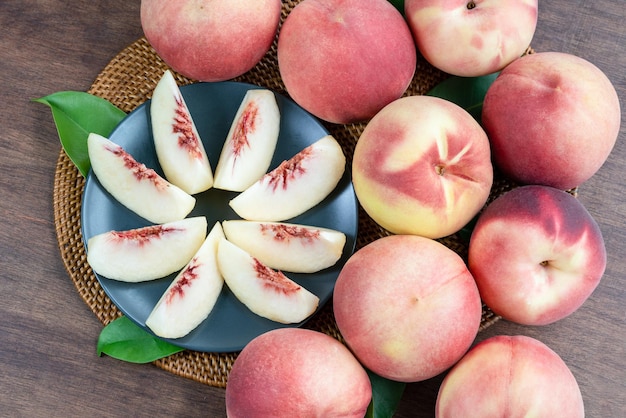 Wit perzikfruit op zwarte plaat op houten tafel