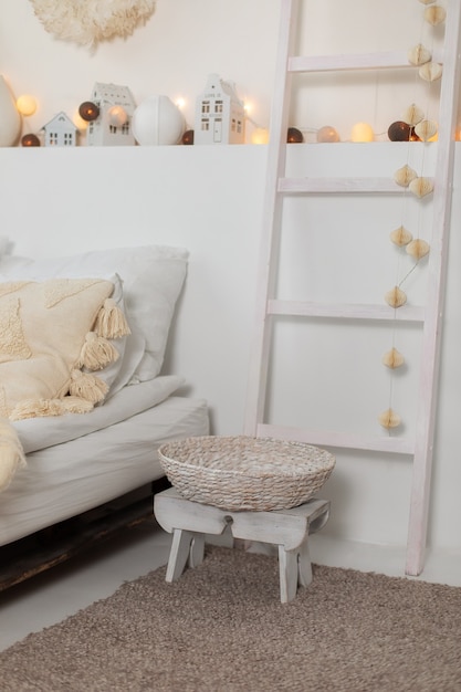 Wit skandinavisch kerstinterieur van slaapkamer met bed en decoratieve houten steplader nieuwjaar