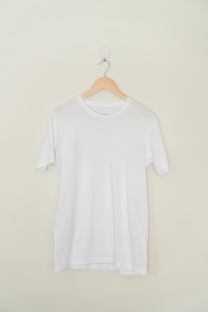 Foto wit t-shirt hangend met houten hanger aan de muur