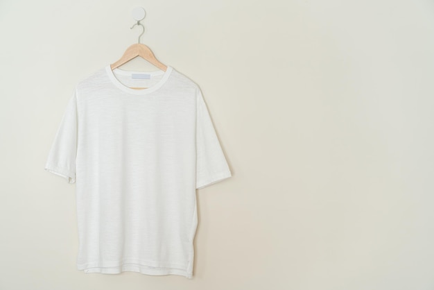 wit t-shirt hangend met houten hanger aan de muur