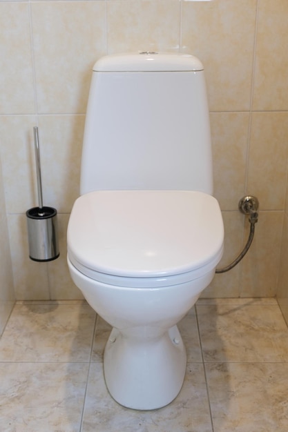 Wit toilet met deksel naar beneden en stortbak in de wasruimte Schoon toilet