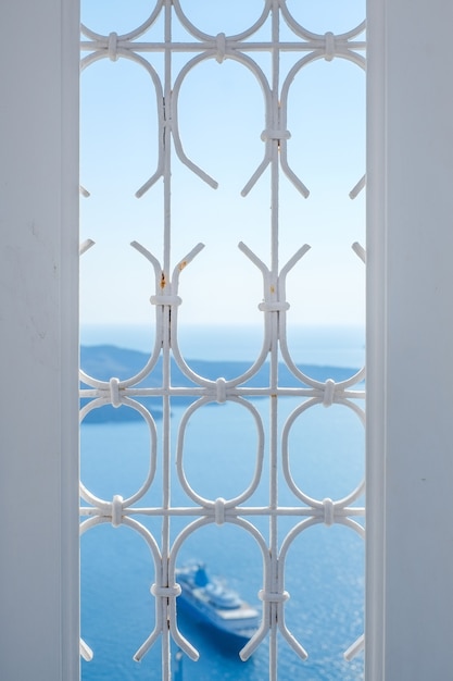 Wit venster en schip in blauwe hemel en overzees in Santorini-eiland, Oia, Griekenland