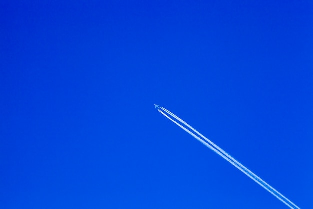 Wit vliegtuig vliegt in de blauwe lucht