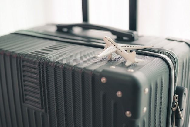 Foto wit vliegtuigmodel op zwarte bagage voor reis en reisconcept