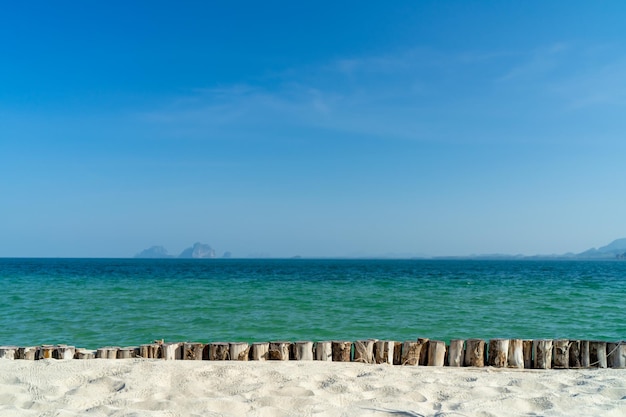 Wit zand met boomomheining met zee en blauwe hemelachtergrond