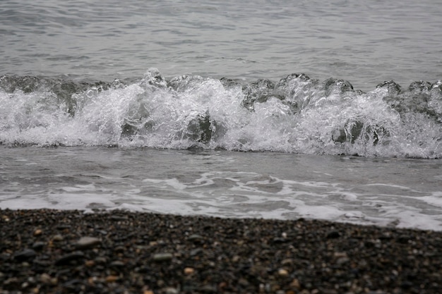 Wit zeeschuim op een rotsachtig kiezelstrand, vloed, storm