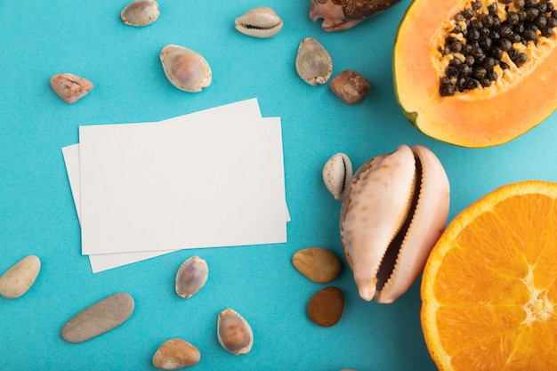 Witboek visitekaartje met rijp gesneden papaya oranje schelpen op blauwe pastel pastel achtergrond Bovenaanzicht kopie ruimte close-up