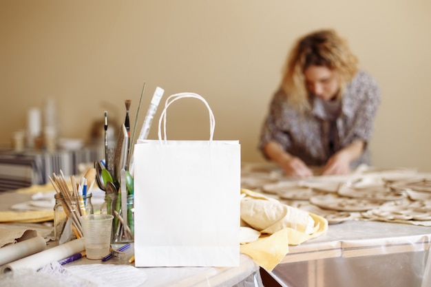 Witboekzak op de achtergrond van de workshop en het meisje die kleiproducten maken