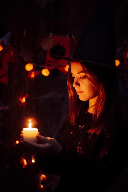 Witch girl with candles in forest at night