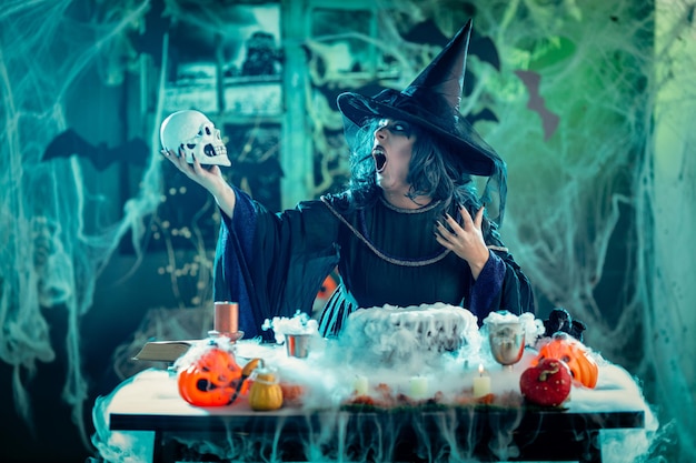 Ведьма с ужасным лицом в жуткой обстановке и дымчато-зеленом фоне разговаривает с мертвыми. Концепция Хэллоуина.