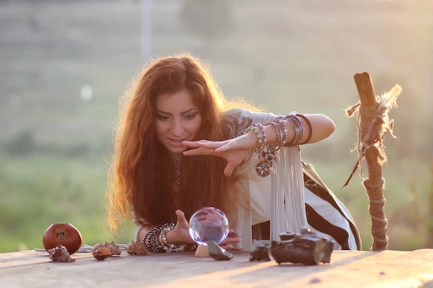 Witch with crystal ball at sunset