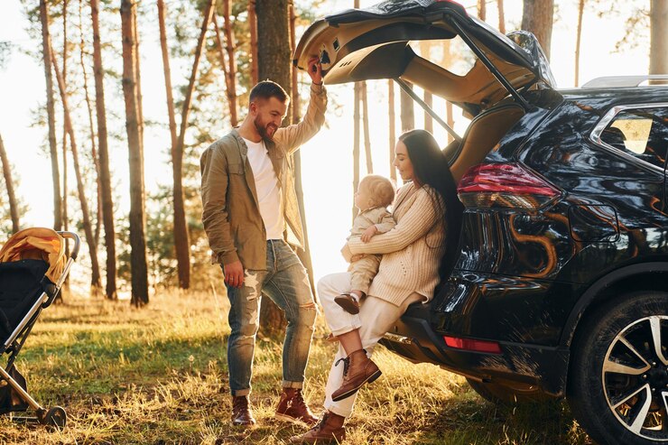 Photo with black colored automobile happy family of father mother and little daughter is in the forest