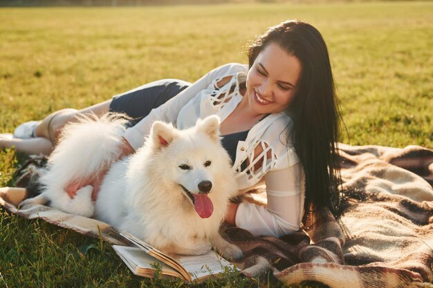 With book Woman with her dog is having fun on the field at sunny daytime