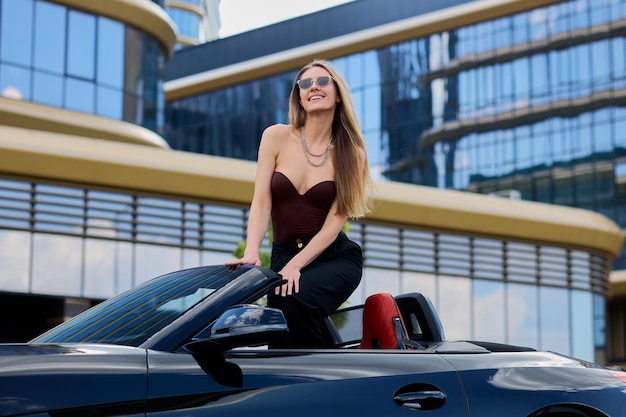 Photo with a contagious smile a woman embraces the excitement of her new convertible car immersing herself in the epitome of a sunny summer day