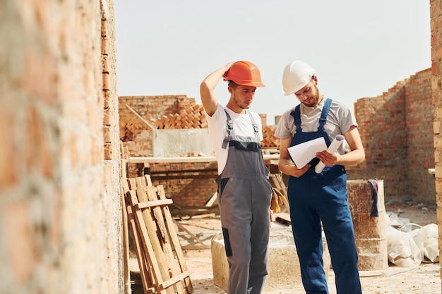 With documents Two construction workers is together at the building