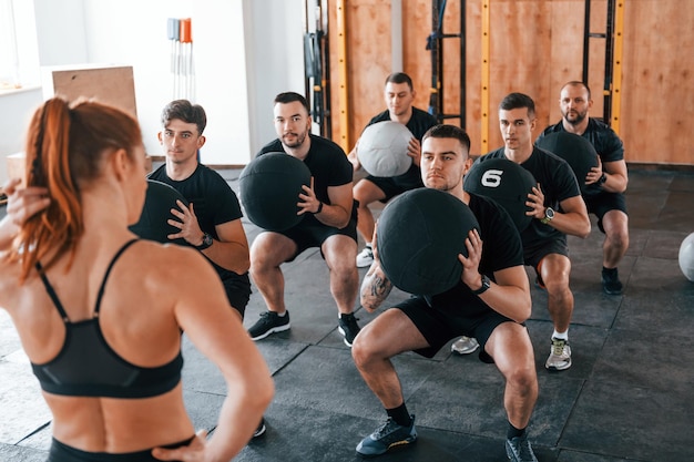 With fitness balls Group of young sportive people have crossfit day indoors in gym