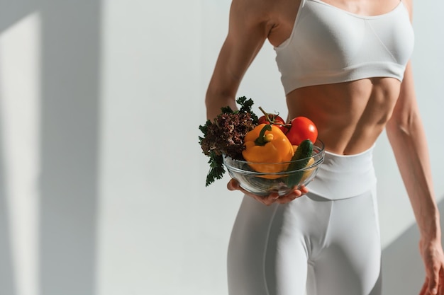 with fruits and vegetables young caucasian woman with slim body shape is indoors in the studio