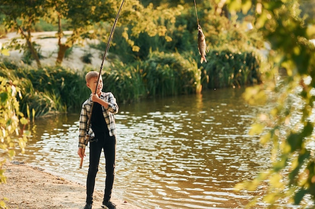 With good catch Boy in casual clothes in on fishion outdoors at summertime