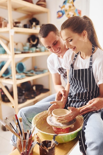 With her boyfriend or husband Young female ceramist have a works indoors with handmade clay product Conception of pottery