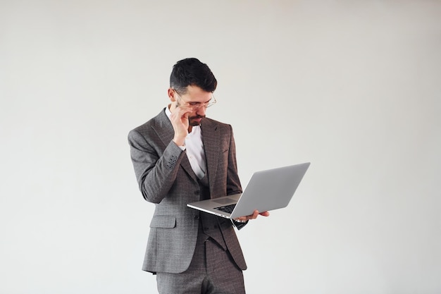 С ноутбуком в руках Молодой стильный бизнесмен в костюме в помещении Концепция успеха