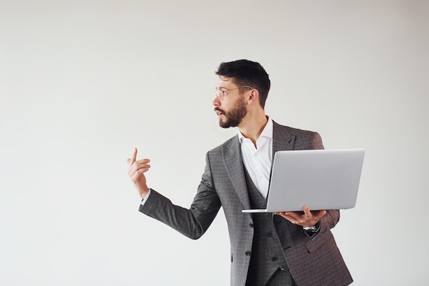 With laptop in hands Young stylish businessman in suit indoors Conception of success