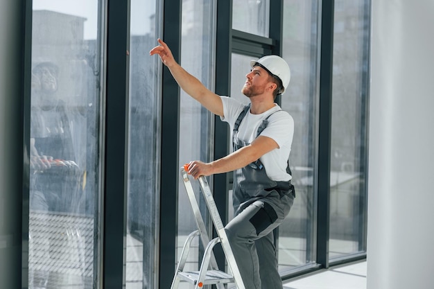 With leader near windows Repairman is working indoors in the modern room