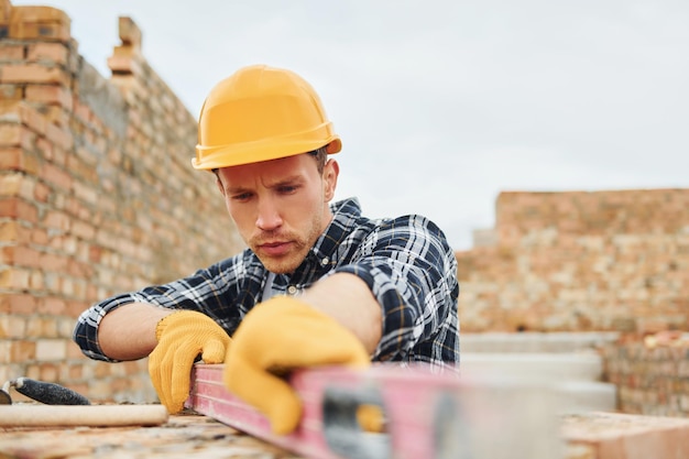 With level measuring tool Construction worker in uniform and safety equipment have job on building