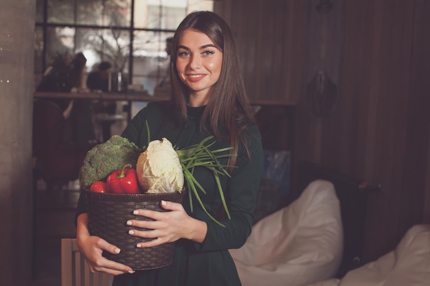 With lots of different vegetables in basket woman is standing