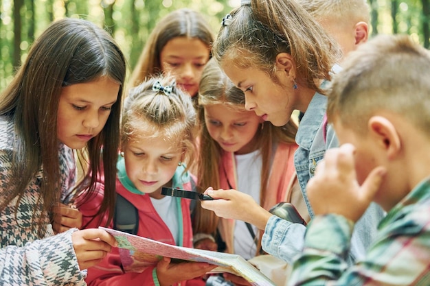 Foto con mappa bambini nella foresta verde durante il giorno d'estate insieme