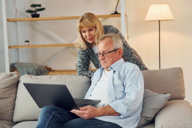 With modern laptop Senior man and woman is together at home