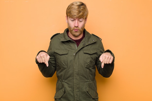 Photo with open mouth pointing downwards with both hands, looking shocked, amazed and surprised