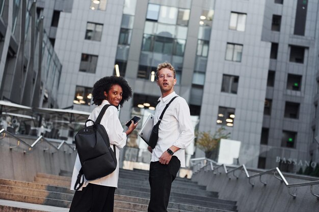 With phone in hands Man with afrian american woman together in the city outdoors