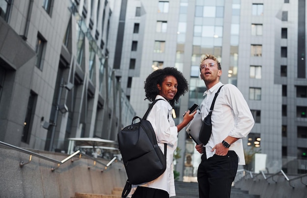 With phone in hands Man with afrian american woman together in the city outdoors