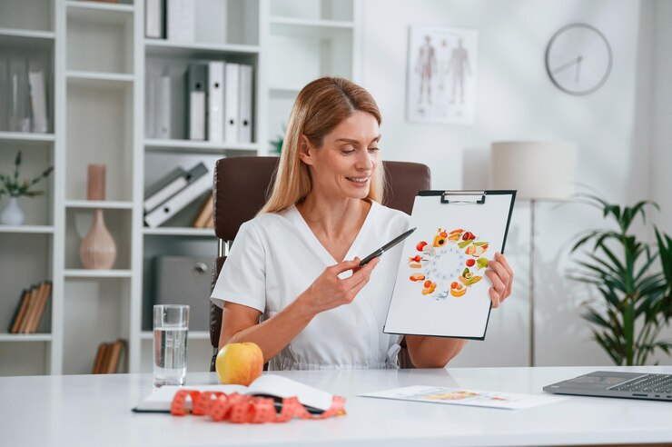 With picture of food and vitamins Young female doctor in white coat is indoors