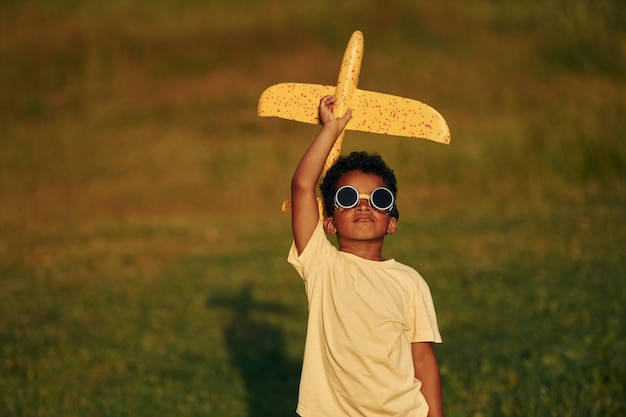 With pilot sunglasses African american kid have fun in the field at summer daytime