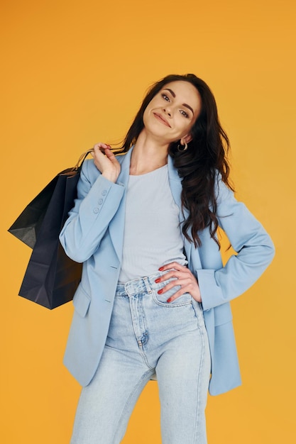 Photo with shopping bags european woman in fashionable stylish clothes is posing indoors