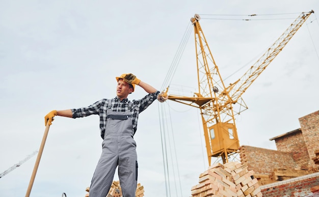 With shovel in hands Construction worker in uniform and safety equipment have job on building