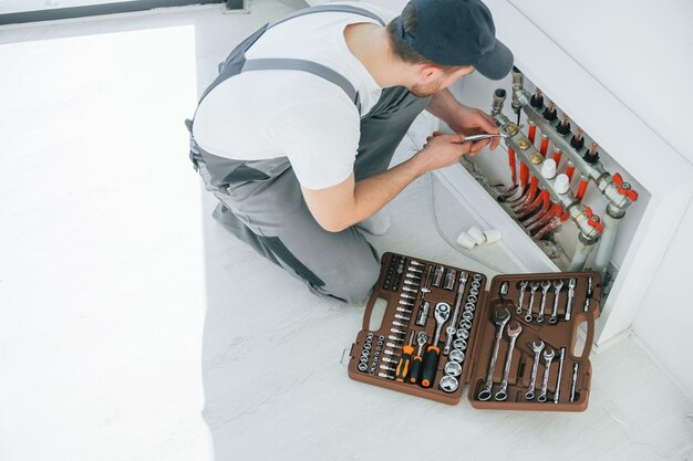 Photo with special tools repairman is working indoors in the modern room