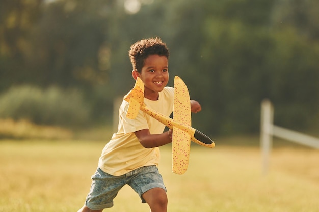 Photo with toy in hands african american kid have fun in the field at summer daytime