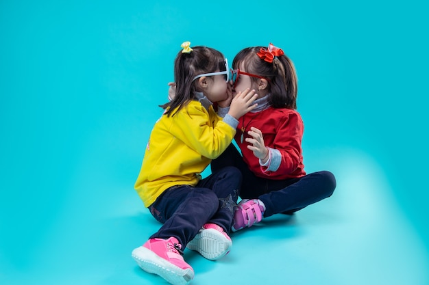 With unusual features. Two twin sisters with genetic disorder playing together on bare floor and touching each other