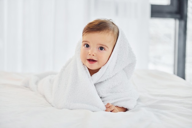 With white towel Cute little baby is indoors in the domestic room