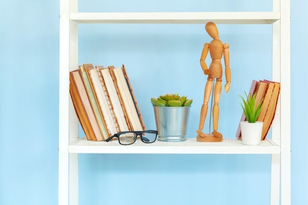 Witmetaalrek met boeken tegen blauwe muur