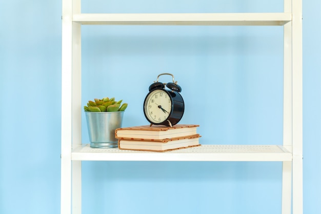 Witmetaalrek met boeken tegen blauwe muur