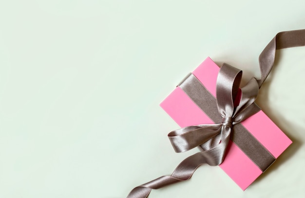 Witte achtergrond met roze geschenkdoos en zilveren lint